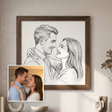 A framed black-and-white portrait sketch of a couple hangs on a beige wall above a console table. A small inset photo in the lower left shows the couple in real life, likely used to illustrate the custom artwork. - Thumbnail 2
