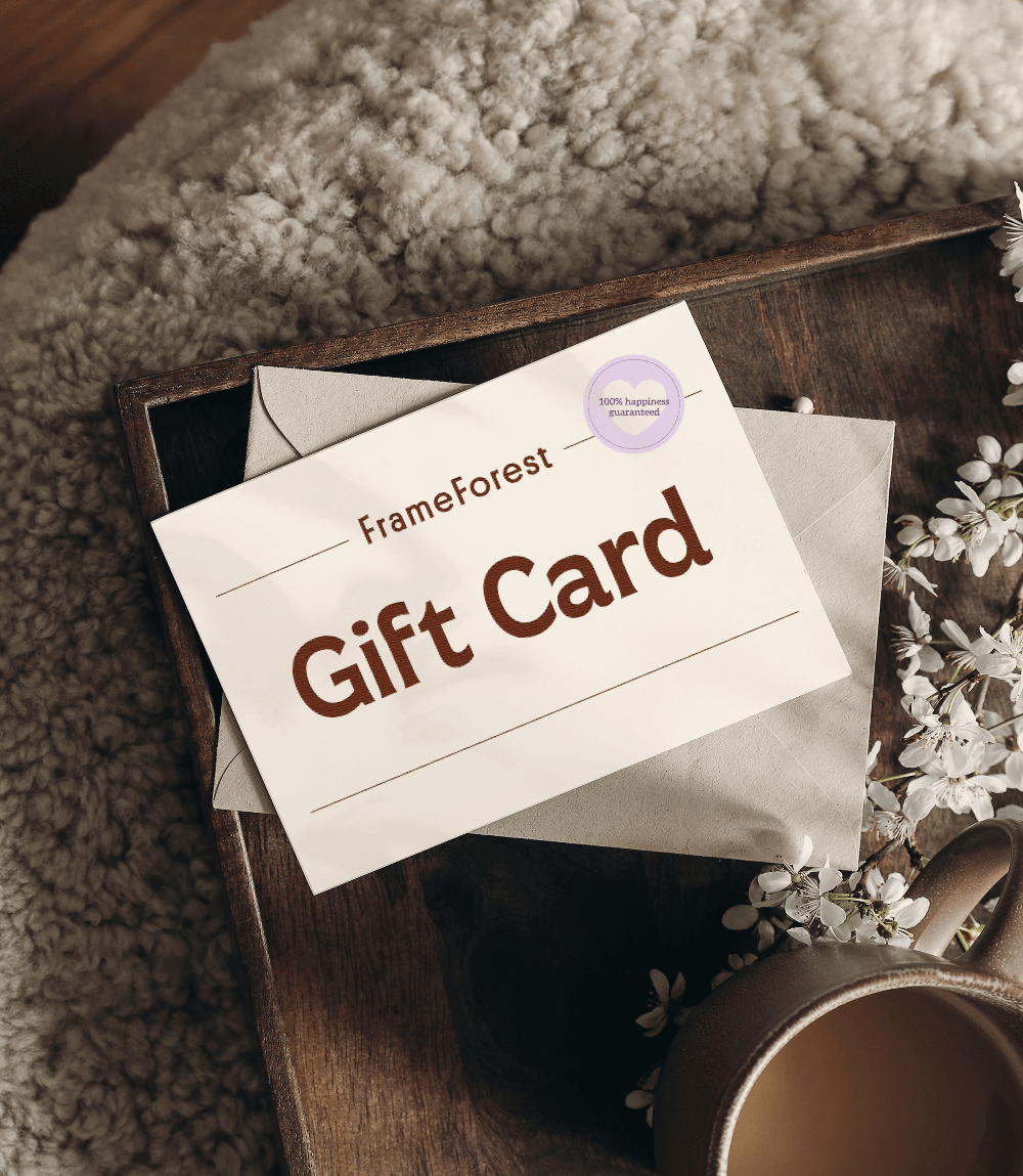 FrameForest gift card on a wooden surface with a cup and flowers