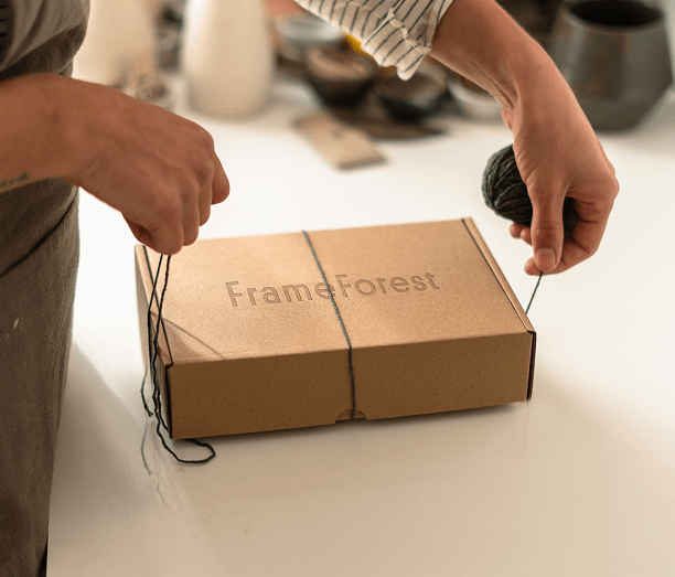Hand-tying a FrameForest package with eco-friendly kraft gift packaging.