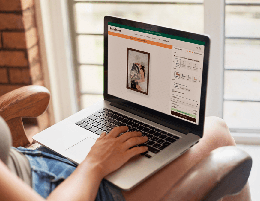 Woman using the FrameForest online picture framing studio to customize a solid wood picture frame.